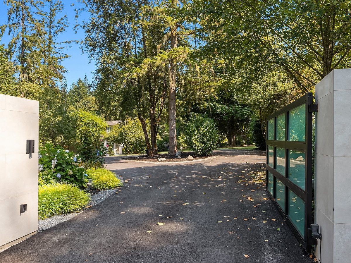 Motorized entry gate opening onto a tree-lined circular driveway