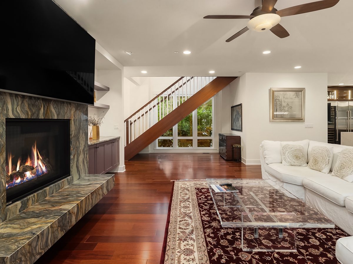 Great room with stone-surround gas fireplace, hardwood floors, and floating staircase
